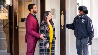 Person holding door for man and woman