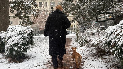 Person holding door for man and woman