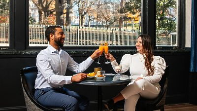 Person holding door for man and woman